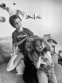 a black and white photo of a woman and two children on a couch